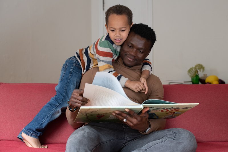 Vater und Sohn auf dem Sofa Vater und Sohn auf dem Sofa, der Vater liest ein Bilderbuch vor