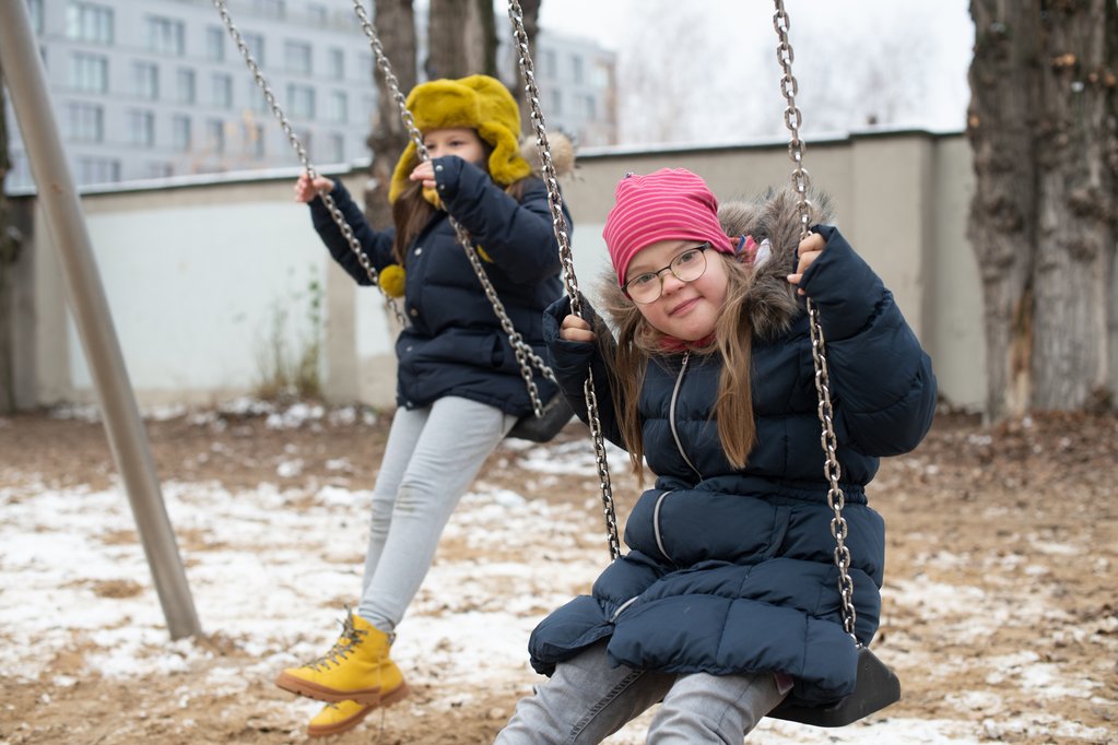 Zwei Kinder schaukeln, ein Kind schaut in die Kamera